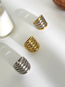 Close-up of multilayered stainless steel rings in gold, silver, and tricolor finishes