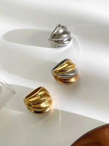 Detalle de tres anillos de acero inoxidable ondulado en acabados oro, plata y bicolor