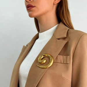 Golden spiral stainless steel brooch pinned on a beige suit lapel for elegant styling