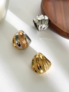 Detalle de anillos anchos ondulados de acero pulido en oro, plata y diseño tricolor