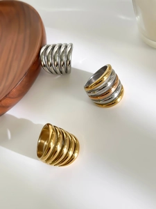 Three multi-layered stainless steel rings in gold and silver finish on a white surface