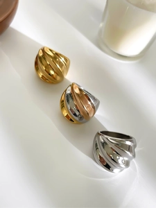 Detalle de anillos anchos con textura de ondas en oro, plata y acero tricolor