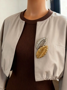 Close-up of gold and silver feather brooch pinned on a grey jacket lapel