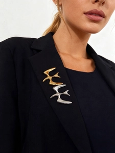 Detailed close-up of polished gold and silver bird brooches on a black blazer lapel