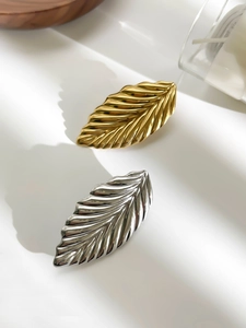 Detailed close-up of golden and silver leaf pins with high-polished metallic textures