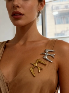 Detail of elegant gold and silver bird brooches on a satin fabric garment