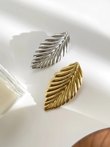 Macro view of gold and silver leaf brooches with realistic plant texture on white background