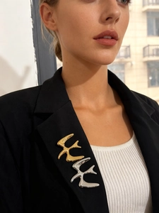 Detail of gold and silver bird brooches pinned on a black blazer lapel for women