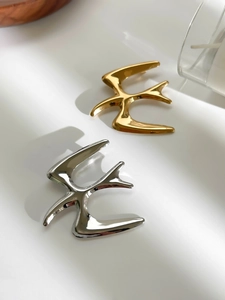 Detailed close-up of bird-shaped stainless steel brooches in polished gold and silver finishes