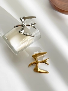 Macro detail of bird-shaped stainless steel brooches in polished gold and silver finishes