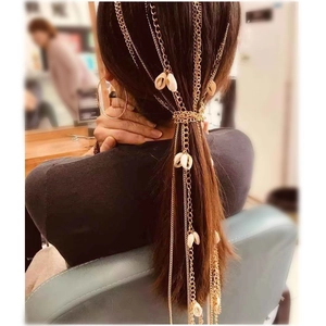 Detail of multi-layered gold hair chain with shell accents styled on a ponytail