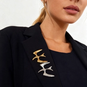 Minimalist flying bird brooches in gold and silver finish on a black suit lapel
