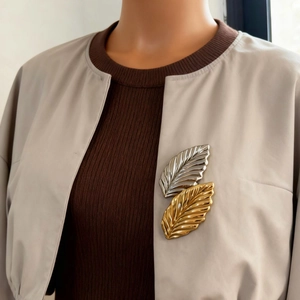Elegant gold and silver overlapping leaf brooch with textured finish on jacket lapel