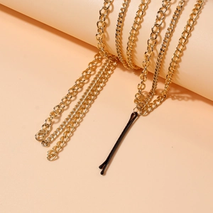 Chic multi-layer gold chain hair accessory with black hair clip pendant on warm background