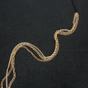 Detail view of multi-layered golden metal fringe hair chain with black elastic strap