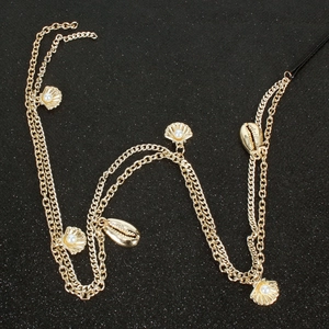Détail de chaîne de tête dorée avec des pendentifs coquillages et perles sur fond noir