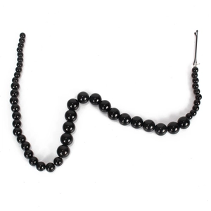 Detail of glossy black gradient faux pearl hair chain beads on white background