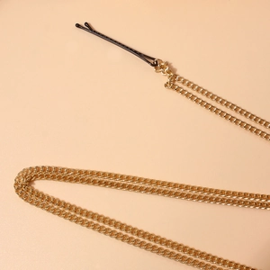 Makroaufnahme einer goldenen Haarkette mit einem eleganten schwarzen Haarclip für Damen