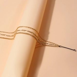 Dreilagiger goldener Ketten-Haarschmuck mit schwarzem Clip auf beigem Zylinder