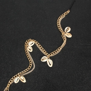 Detail of bohemian gold metal chain headpiece with white cowrie shells on black background