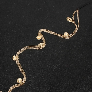 Chaîne de tête multicouche dorée avec breloques coquillages et perles sur fond noir