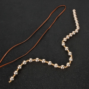 Minimalist beaded hair tie with polished silver and gold beads on brown leather cord