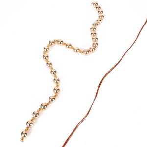 Golden beaded hair accessory with brown leather cord for women, minimalist style