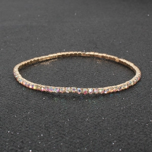 Sparkling rainbow rhinestone elastic bracelet with gold base on a textured black background