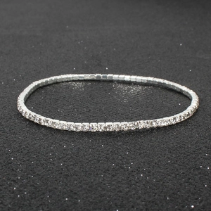 Macro detail of sparkling silver rhinestone tennis bracelet on a black textured background