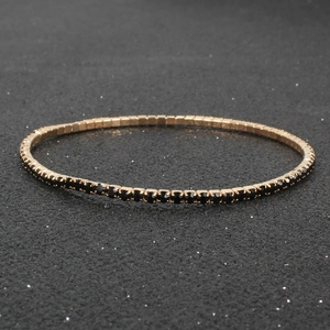 Macro view of gold-plated tennis bracelet with intricate black crystal inlay detail