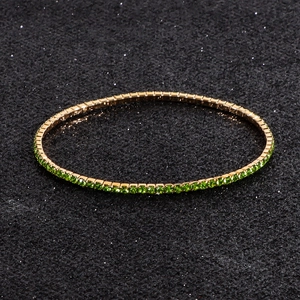 Macro detail of elastic tennis bracelet with green crystals and gold-plated finish