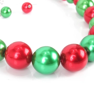 Dettaglio macro della collana di perle rosse e verdi con elementi a tema natalizio