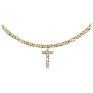 Macro detail of gold tennis chain featuring iced out letter T pendant with white crystals