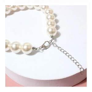 Details von weißem Perlen-Halsband mit silbernem Karabinerverschluss und Metallkette
