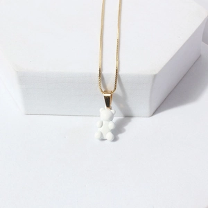 Close-up of a cute white resin bear pendant on a thin gold chain against white background