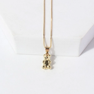 Macro view of gold dainty chain necklace featuring a glossy 3D teddy bear pendant