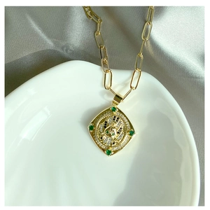 Gros plan détaillé du collier trombone doré avec pendentif religieux serti de diamants fins
