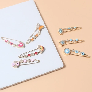 Detail showing seven rhinestone safety pin brooches with heart, star and evil eye motifs