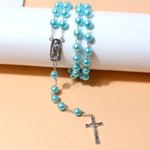 Close-up of blue pearl rosary necklace with silver crucifix and Mary medallion on white stand