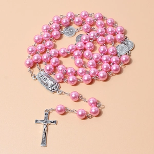 Macro detail of pink pearl rosary necklace featuring a silver crucifix and religious medal