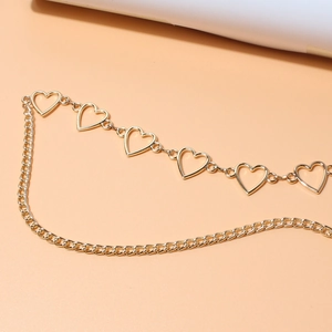 Close-up of golden hollow heart links and slim metal chain detail for waist accessory