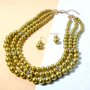 Detail of multi-layer champagne green pearl necklace with gold diamond cross spacers