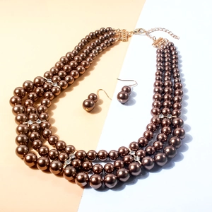 Detail of four-layer brown faux pearl necklace with gold-tone hardware and rhinestone spacers