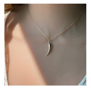 Collana con ciondolo cornicello in oro lucido e catena a croce su modella