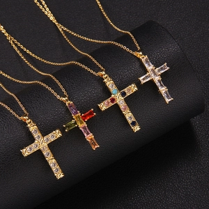 Cross necklaces with colorful zircon stones in gold plating on a black leather stand