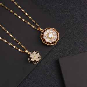 Golden rotating necklace set with clover and floral zircon pendants on black leather background