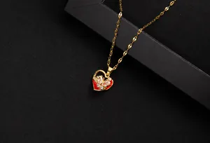Detail view of a gold heart pendant with a rotating zircon butterfly and red enamel inlay