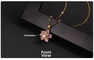 Detail of a rotating gold clover necklace with pink heart crystals and a center zircon