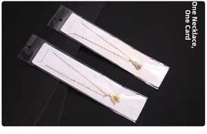 Macro view of gold stainless steel zircon elephant and clover pendants in card packaging