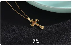 Macro side view of a gold cross pendant with colorful zircon stones and floral engraving